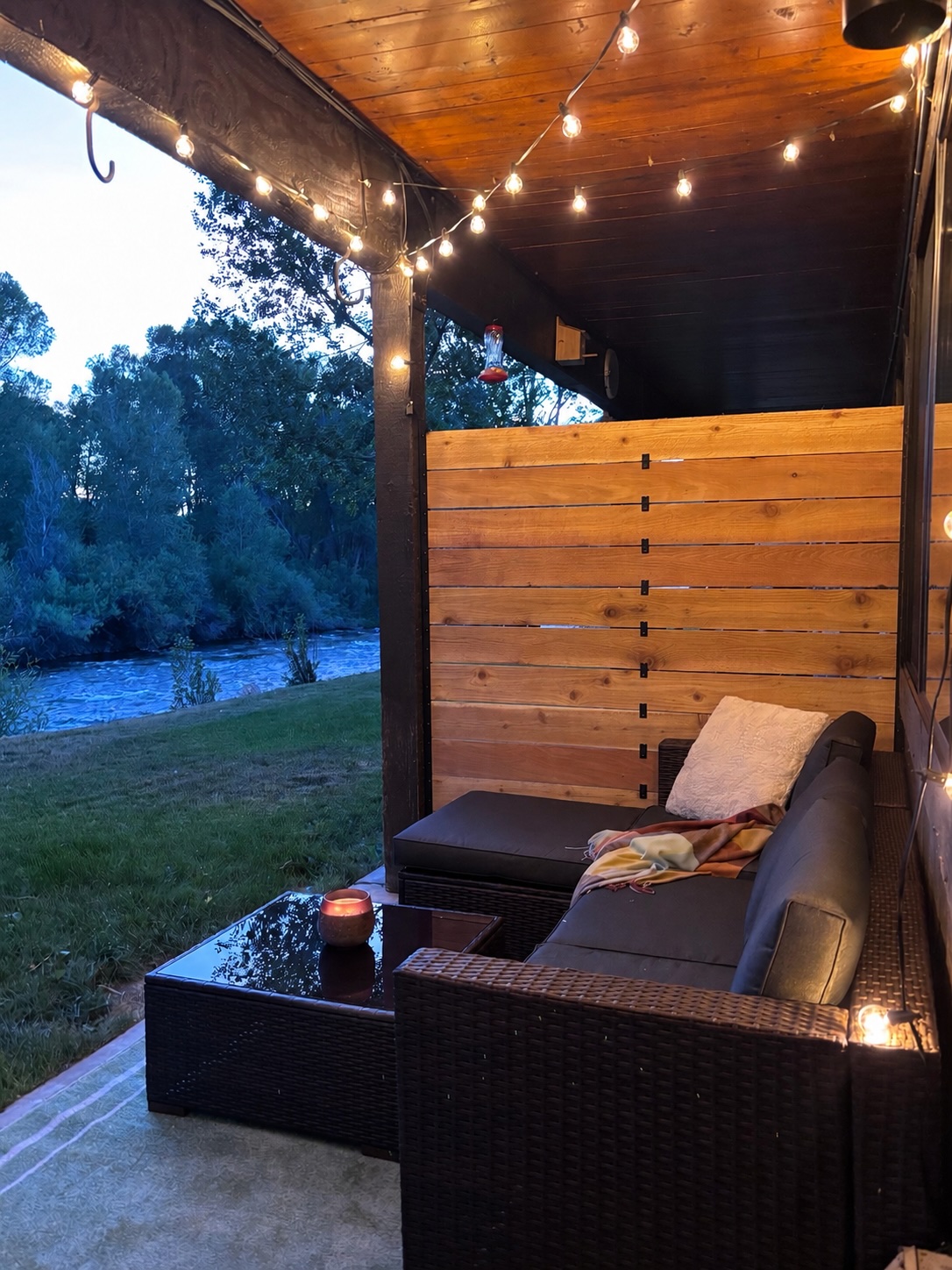 Riverside patio at dusk with string lights overlooking the Roaring Fork