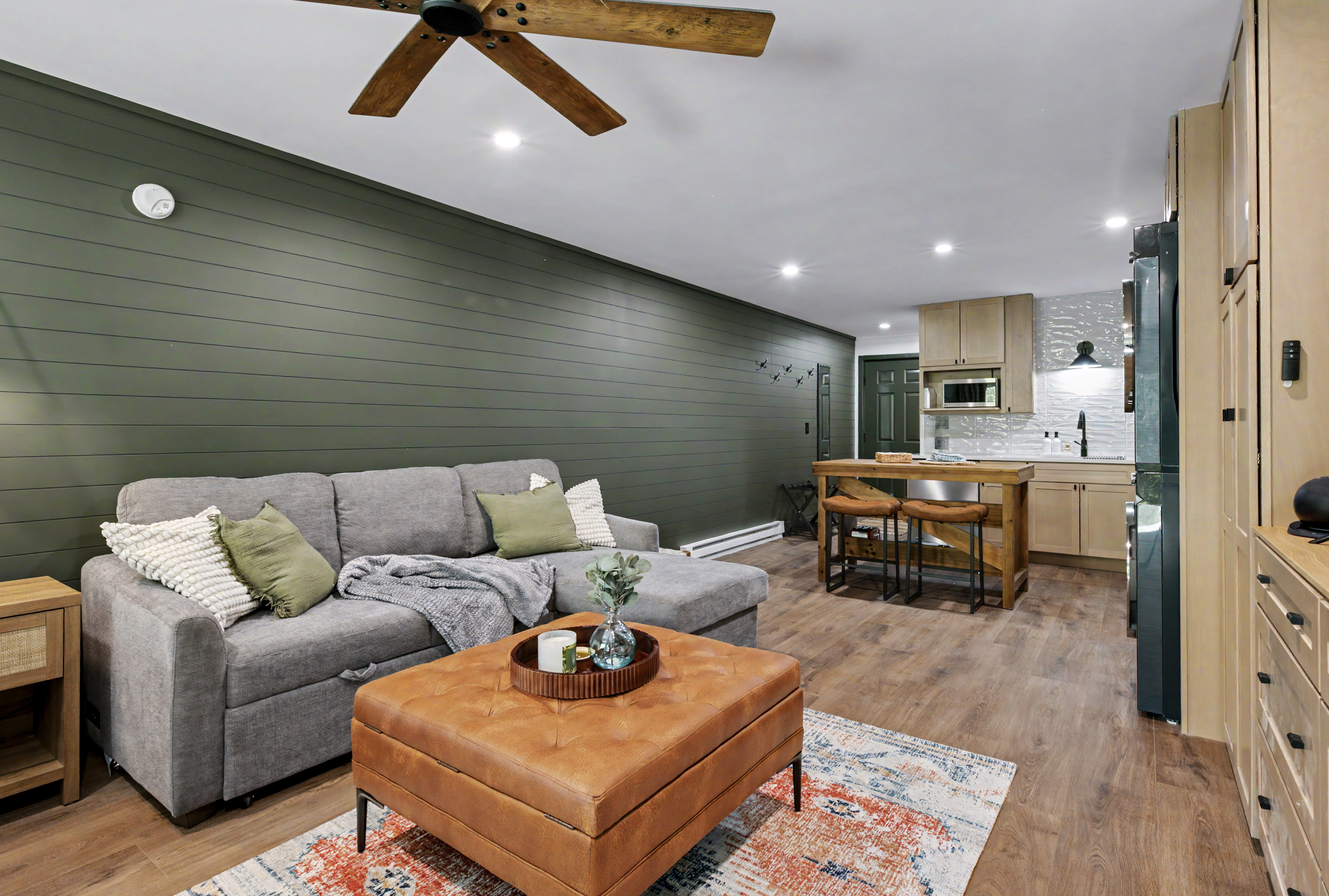 Living room with green shiplap wall and kitchen view