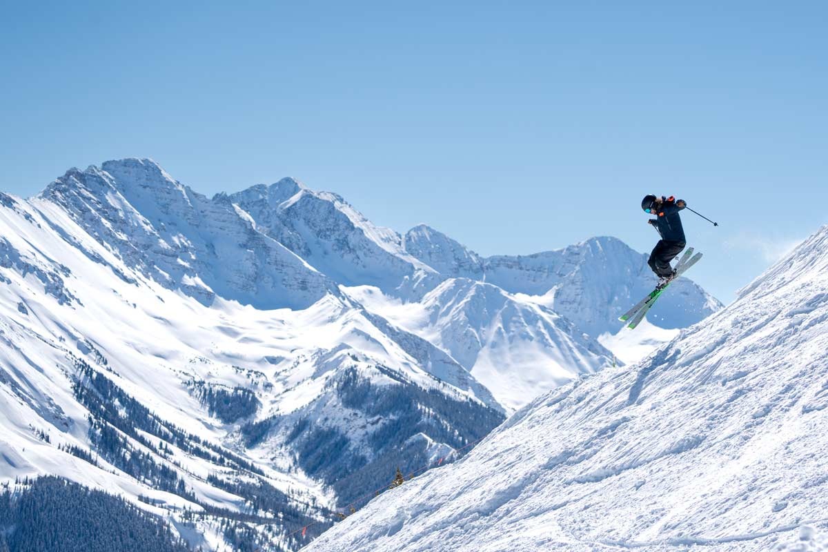 Skier jumping with snow-capped mountains in the background